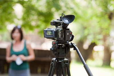 Close-up of television camera against woman at park