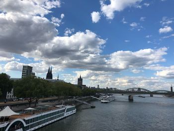 Bridge over river by buildings in city against sky