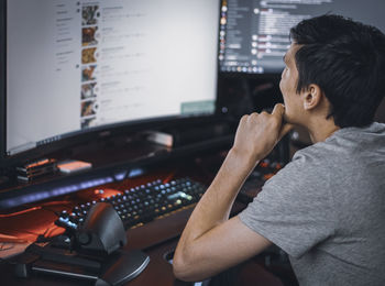 A young caucasian guy sits in a work chair and browses an online menu for ordering takeaway food
