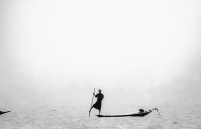 Silhouette man on boat in sea