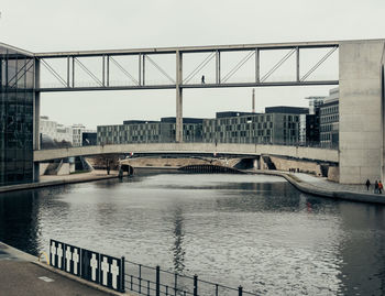 Bridge over river in city against clear sky