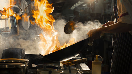 Chef stir fry cooking on wok with fire hard in kitchen