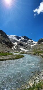 Scenic view of lake by mountains against blue sky