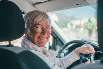Portrait of senior woman with eyeglasses sitting in car