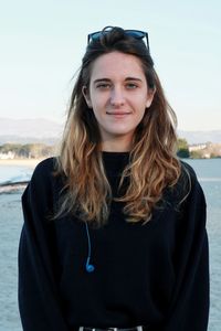 Portrait of smiling young woman standing against sea and sky