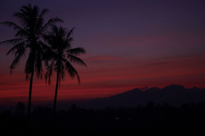 Silhouette palm trees against romantic sky at sunset