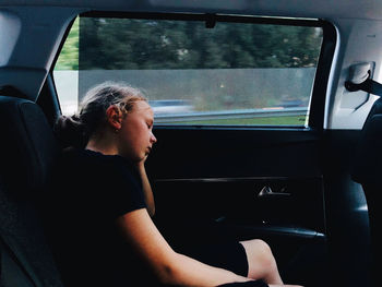 Side view of woman sitting in car