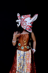 Midsection of woman standing against black background