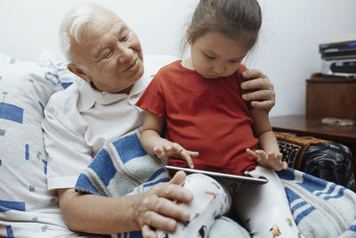 Grandfather and granddaughter with digital tablet at home