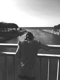 Rear view of woman standing at beach against clear sky