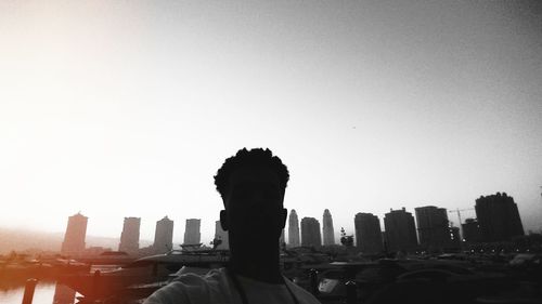 Silhouette of man in city against clear sky