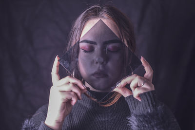 Portrait of young woman holding camera over black background