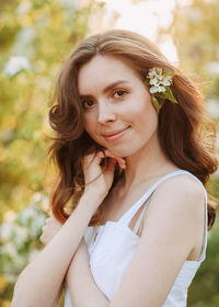 A cute happy young woman with a hairstyle in a white dress is walking enjoying nature in the summer