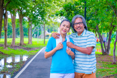 Portrait of smiling couple standing against trees in park