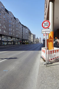 Road sign by street against buildings in city