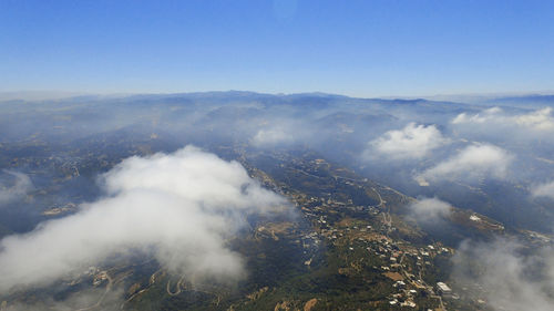Aerial view of clouds over mountains against clear sky