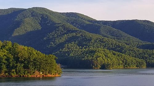 Scenic view of river by mountains against sky