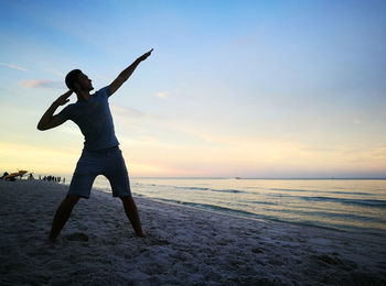 Man posing against sea during sunset