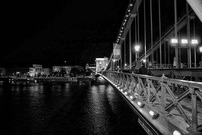 Illuminated bridge over river against sky at night