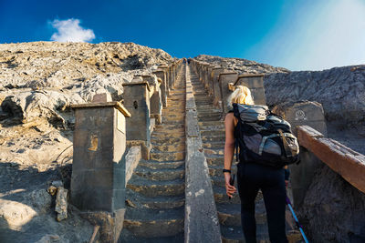 Rear view of woman walking on staircase against sky