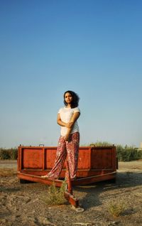 Portrait of young woman on a wagon standing next to the clear blue sky. 