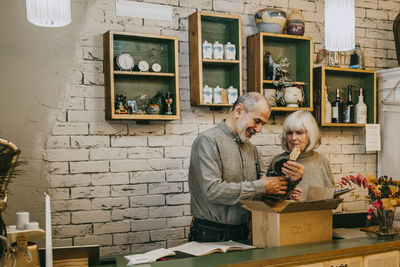 Male and female senior owners unpacking merchandise at home decor shop