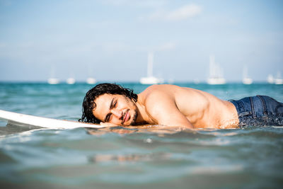 Portrait of shirtless man in sea against sky