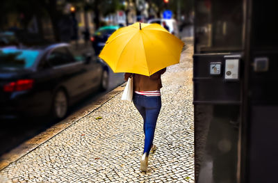 Rear view of woman with umbrella walking in rain