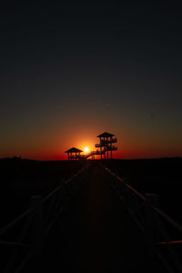 Silhouette railroad tracks against sky during sunset