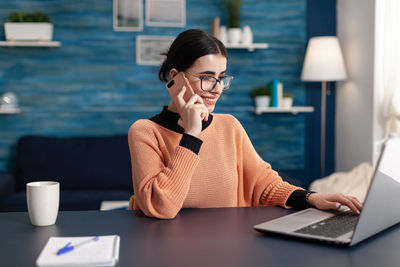 Midsection of woman using mobile phone while sitting on table