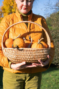 Middle-aged blond caucasian woman in a yellow demi-season jacket with pumpkins