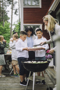 Grandmother with grandchildren taking barbecue food during party