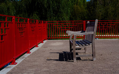 Empty wooden bench in the park surrounded by red railing