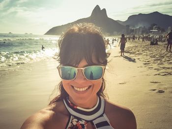 Portrait of woman smiling while wearing sunglasses at beach