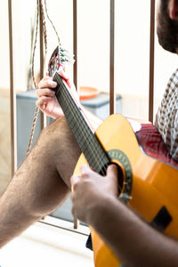 Midsection of man playing guitar