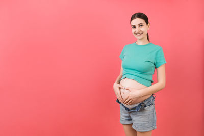 Portrait of a smiling young woman against red background