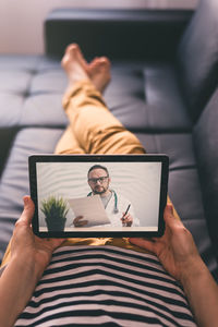 Woman lying on a sofa and talking with a doctor online using digital tablet. telemedicine concept.