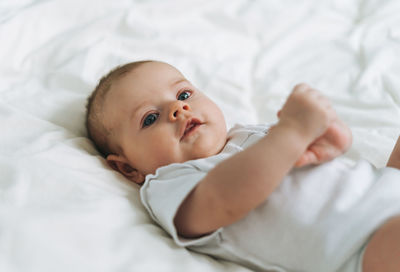 Cute baby girl 2-4 month on the bed with white linen, natural tones, selective focus