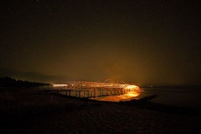 Scenic view of illuminated sea against sky at night