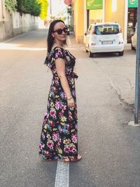 Young woman wearing sunglasses standing on street in city