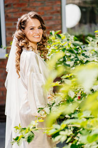 Portrait of smiling young woman standing against white wall