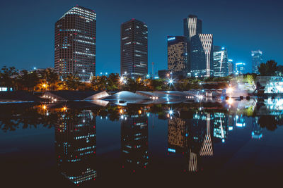 Illuminated modern buildings against sky at night