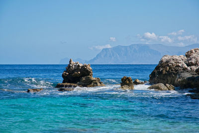 Rock formation in sea against blue sky