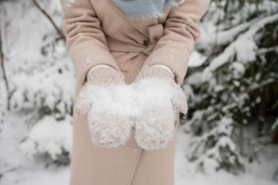 Women's mittened hands keep the snow outside in winter