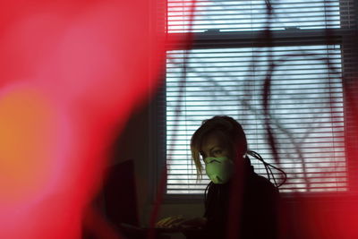 Side view of girl standing against window at home