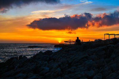 Silhouette man at beach against sky during sunset