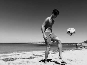 Man playing soccer on beach against sky