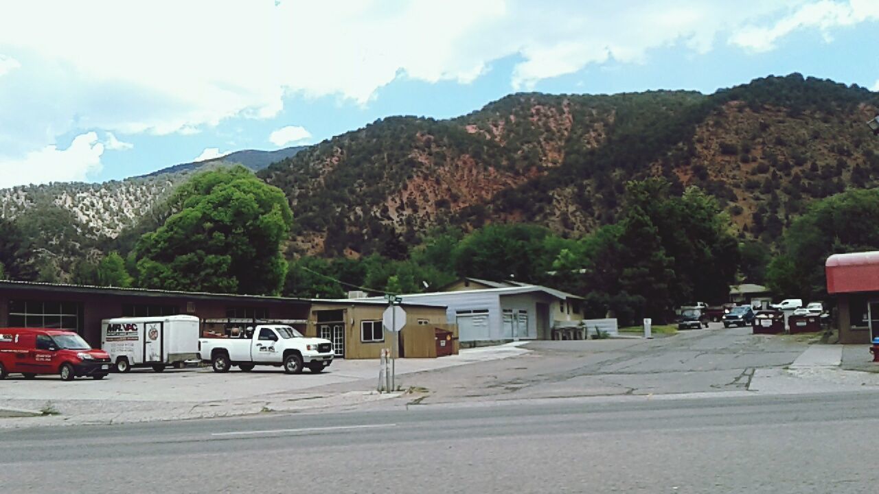 VEHICLES ON ROAD AGAINST MOUNTAINS