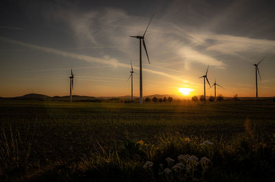 Scenic view of windmills on field against sky during sunset