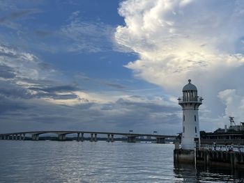 Bridge over sea against cloudy sky